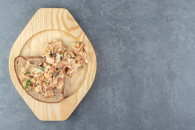 Salade d'oeufs et pain sur plaque de bois.