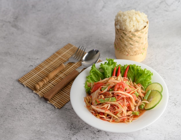 Photo gratuite salade de papaye thaïlandaise dans une assiette blanche avec du riz gluant