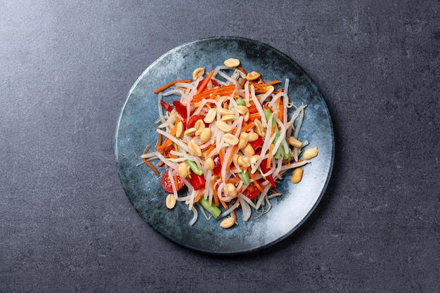 Photo gratuite salade de papaye verte som tam thaï sur un fond d'ardoise noire