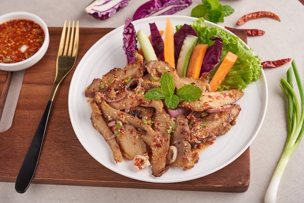Salade de porc grillé cuisine thaïlandaise avec des ingrédients aux herbes et épices, cuisine traditionnelle du nord-est délicieuse avec des légumes frais, menu de porc grillé tranche chaude et épicée cuisine asiatique. Porc grillé avec trempette épicée.