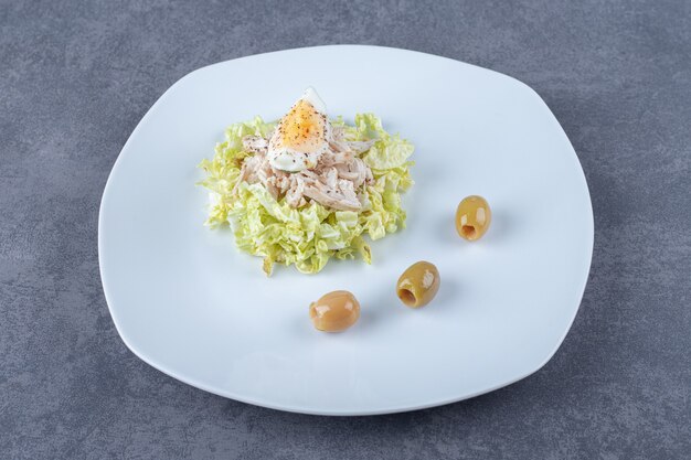 Salade de poulet bouilli et d'oeufs sur une assiette blanche.