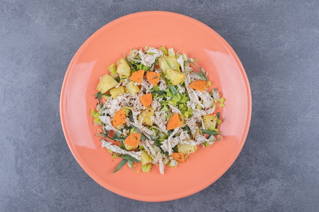 Salade de poulet émincé sur plaque orange.