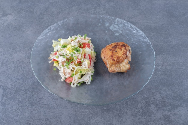 Salade de poulet et légumes grillés sur plaque de verre.