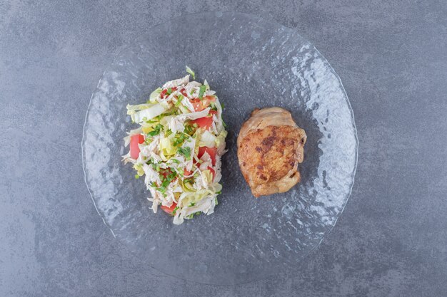 Salade de poulet et légumes grillés sur plaque de verre.