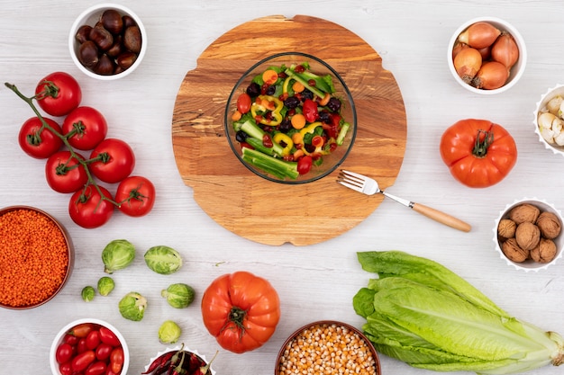 Salade de printemps sur la planche de bois entourée de différents légumes frais