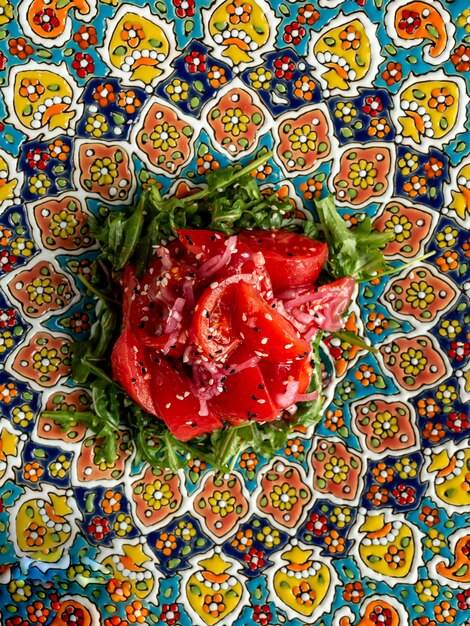 salade avec tomate rouge oignon rugula huile et sésame sur plaque