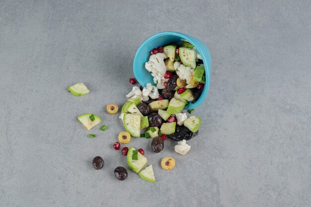 Salade verte dans une tasse bleue avec olives noires et pommes