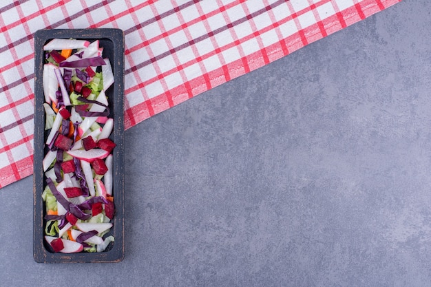 Salade verte avec des ingrédients dans un plateau noir.