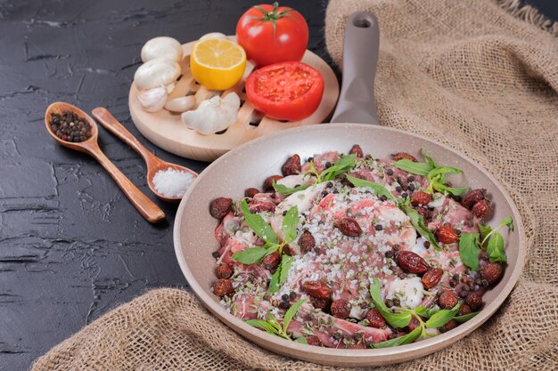 Salade de viande crue à la menthe fraîche dans une casserole et assiette de légumes frais.