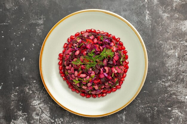 Salade de vinaigrette vue de dessus avec des grenades et des haricots sur une surface grise