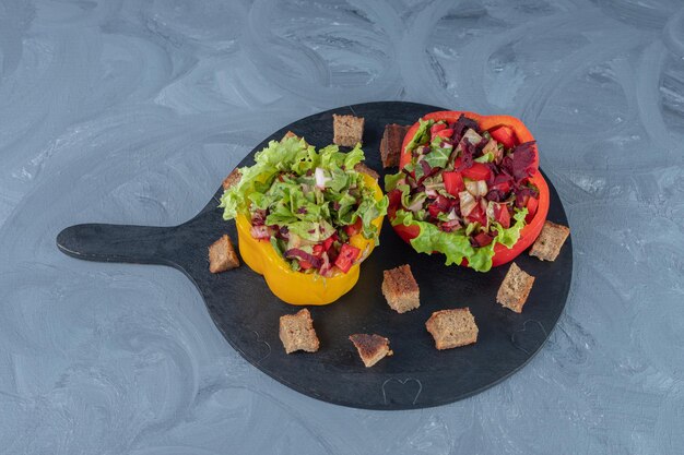 Salades de légumes portionnées en tranches de poivron sur un plateau de service sur une table en marbre.