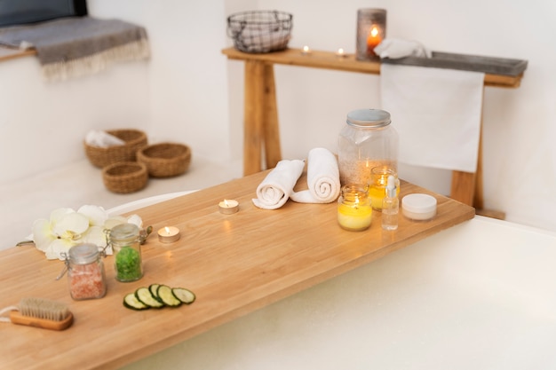 Salle de bain avec bougies, serviettes, produits de spa et baignoire remplie d'eau