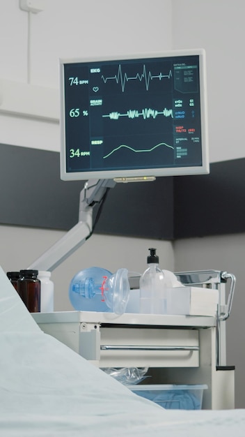 Salle d'hôpital avec moniteur de fréquence cardiaque pour les soins de santé et la récupération. Personne aux urgences avec un lit vide et du matériel médical pour la réanimation et une assistance médicale pour la guérison.