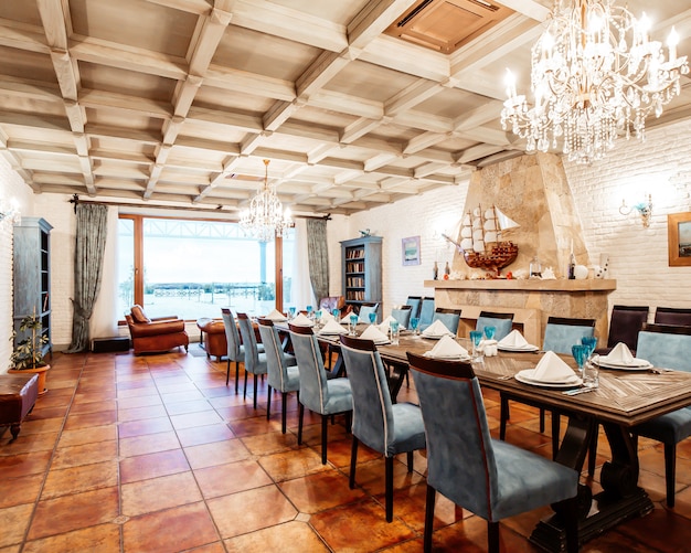 Photo gratuite salle privée du restaurant_ avec chaises bleues, murs blancs, cheminée et grande fenêtre