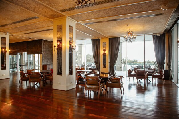 Salle de restaurant avec fauteuils en cuir et portes-fenêtres