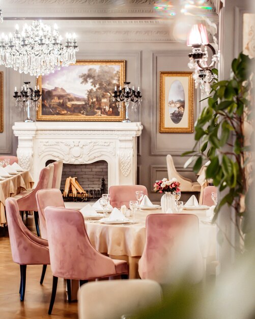 Salle de restaurant avec table ronde quelques chaises cheminée et plantes