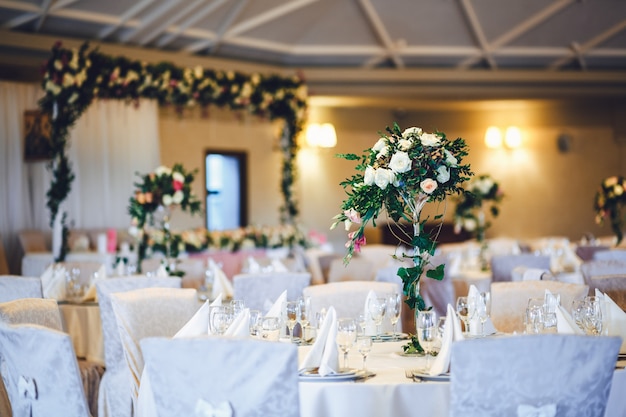 Salle de restaurant avec des tables décorées de grands vases avec des roses