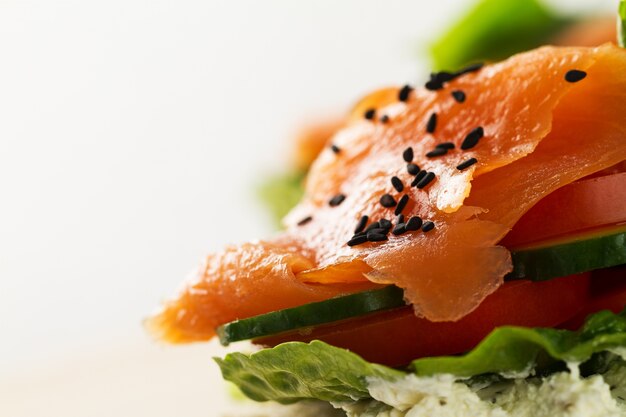 Salmon salé savoureux et coloré avec des légumes sur sandwich. Fond clair. Espace de copie.