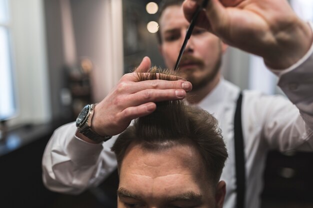 Salon de coiffure floue coupe les cheveux du client masculin
