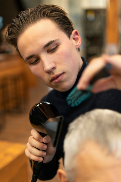 Salon de coiffure en gros plan tenant un sèche-cheveux