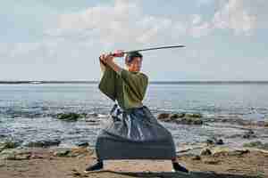 Photo gratuite samouraï avec épée à la plage