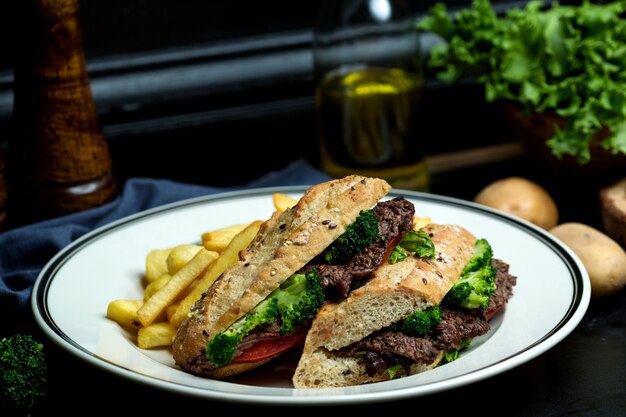 Sandwich au bœuf au brocoli, tomates au pain servi avec frites