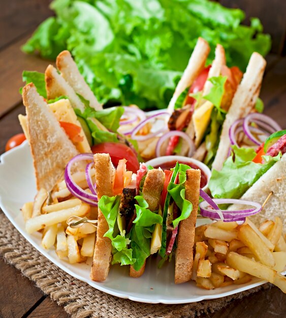 Sandwich club au fromage, concombre, tomate, viande fumée et salami. Servi avec frites.