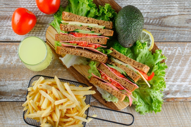 Sandwich à la limonade, avocat, frites, tomates à plat sur planche de bois et à découper