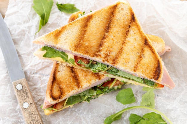Photo gratuite sandwich panini au jambon, fromage, tomate et roquette sur table en bois
