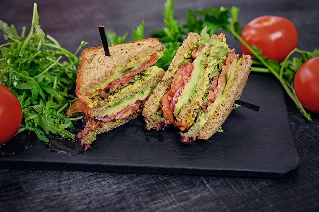 Sandwich végétarien avec salade et tomates sur une surface de table en bois.