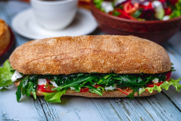 Sandwich vue latérale avec fromage mozzarella aux tomates et roquette sur la table