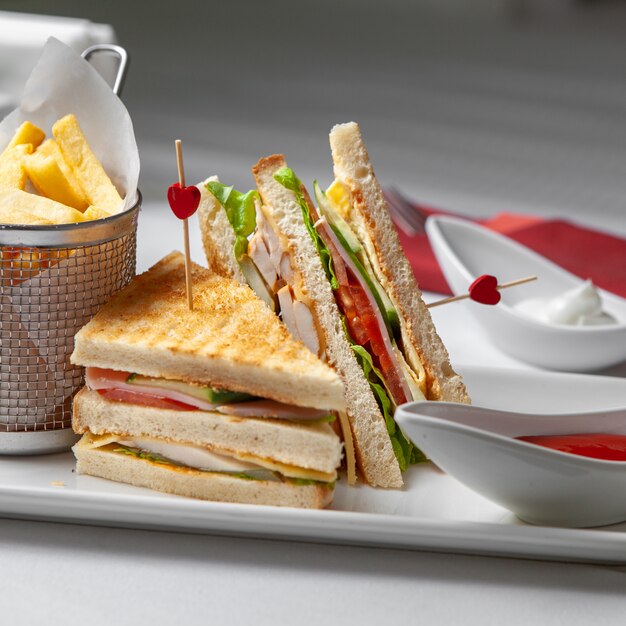 Sandwich vue latérale sur table avec frites, ketchup sur fond blanc.