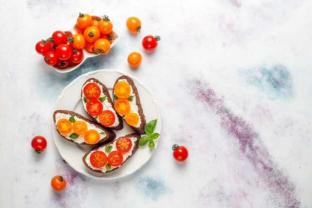 Sandwiches ouverts avec fromage cottage, tomates cerises et basilic.