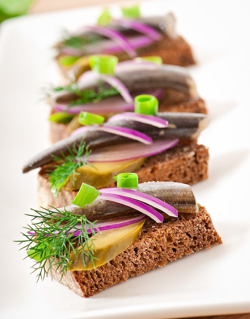 Sandwiches de pain de seigle au hareng, oignons et herbes.