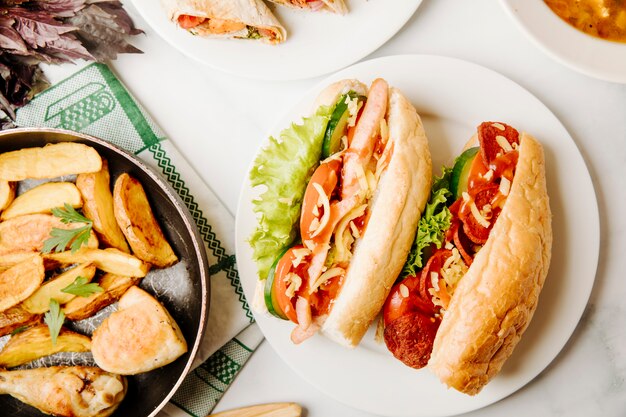 Sandwichs au pain avec mélange d'aliments à l'intérieur et poulet grillé avec pommes de terre à la poêle.