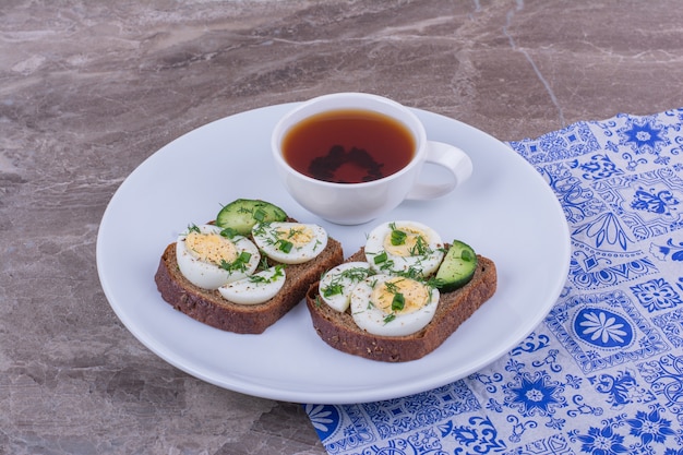 Sandwichs aux œufs durs et aux herbes avec une tasse de thé.