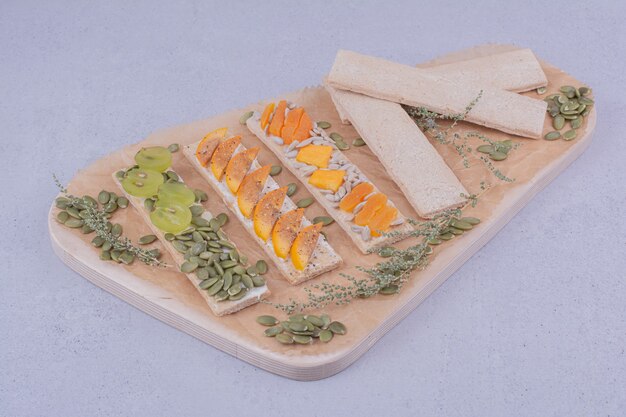 Sandwichs cracker aux herbes et fruits sur une planche de bois