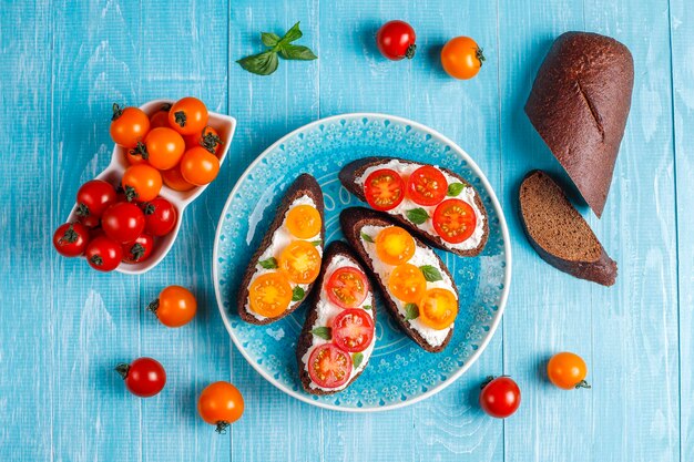 Sandwichs ouverts avec fromage cottage, tomates cerises et basilic.