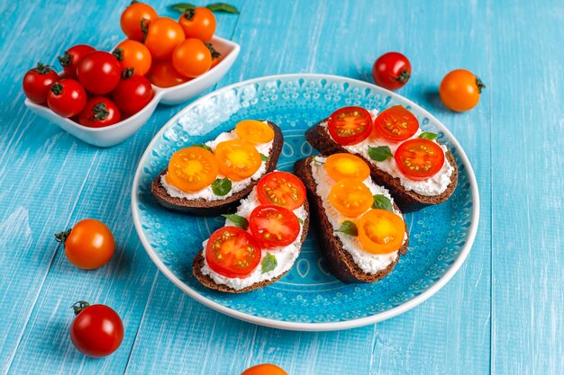 Sandwichs ouverts avec fromage cottage, tomates cerises et basilic.