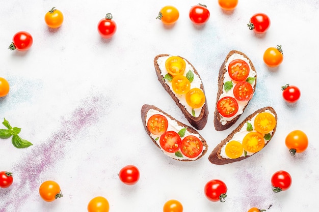 Photo gratuite sandwichs ouverts avec fromage cottage, tomates cerises et basilic.