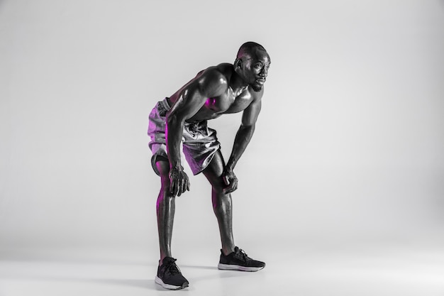 Sans peur. Photo de Studio de formation de jeune bodybuilder afro-américain sur fond gris. Modèle masculin unique musclé debout dans le sportwear. Concept de sport, musculation, mode de vie sain.