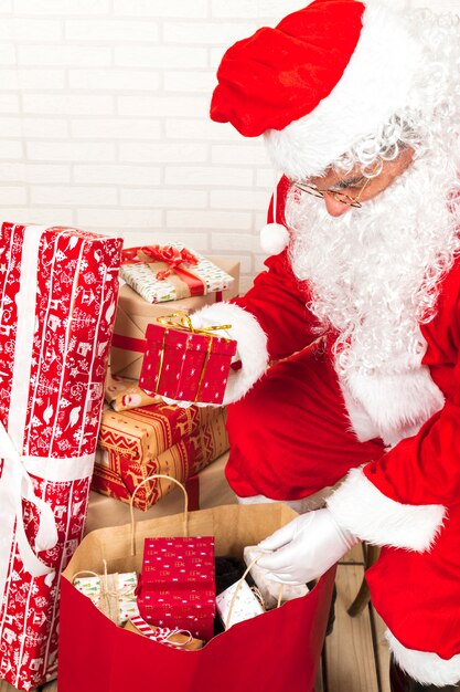 Santa Claus met des boîtes-cadeaux dans un grand sac