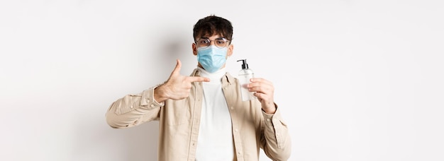 Photo gratuite santé covid et concept de quarantaine joyeux jeune homme dans un masque facial et des lunettes pointant du doigt bo