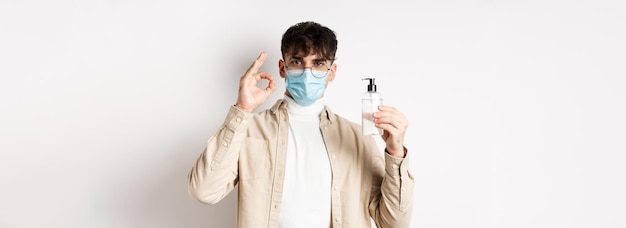 Photo gratuite santé covid et concept de quarantaine portrait d'un homme naturel dans des verres et un masque facial montrant une bouteille