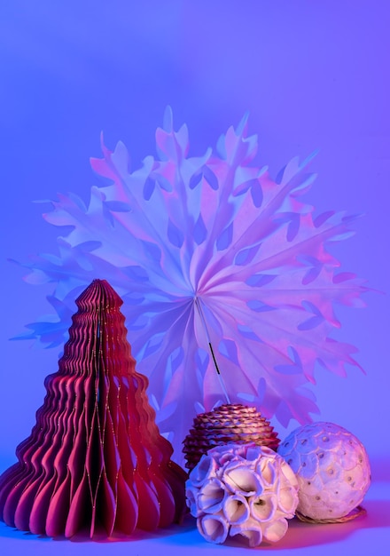 Photo gratuite sapins de noël en papier décoratif sur fond bleu avec néon tendance