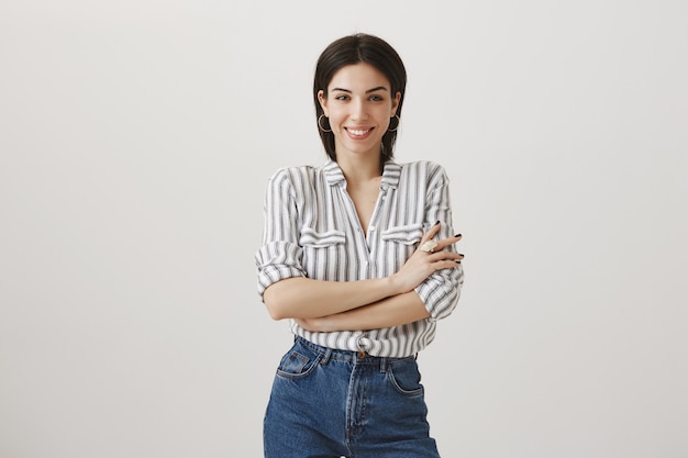 Sassy femme confiante croise les mains sur la poitrine, souriant et à la recherche de détermination