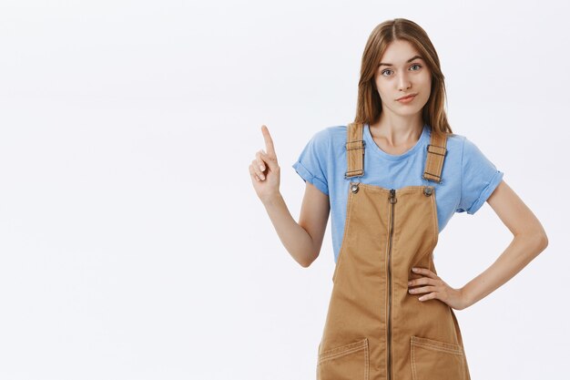 Sassy jeune étudiante secouant le doigt ou pointant vers le haut