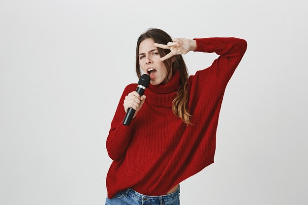 Sassy jolie femme chantant au karaoké, montrer le signe de la paix