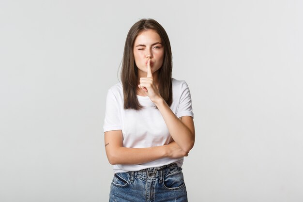 Sassy jolie fille brune clignant des yeux, chutant à la caméra, ont un secret.