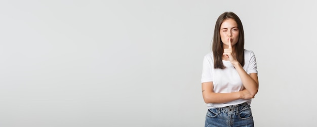 Sassy jolie fille brune faisant un clin d'œil chut à la caméra a un secret